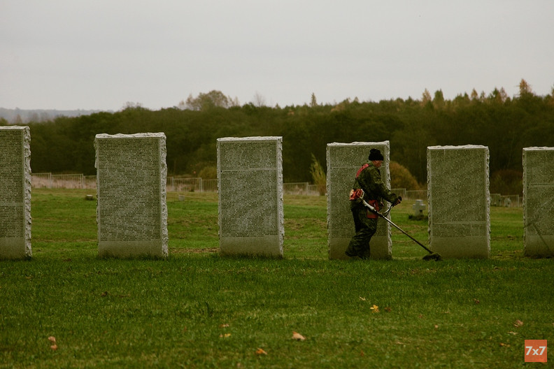 Дворник стрижет траву на немецком кладбище